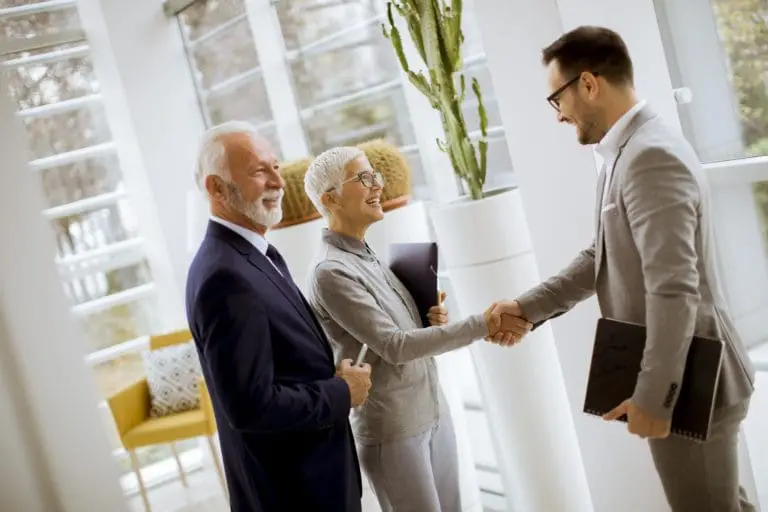 Young businessman with senior clients standing in office