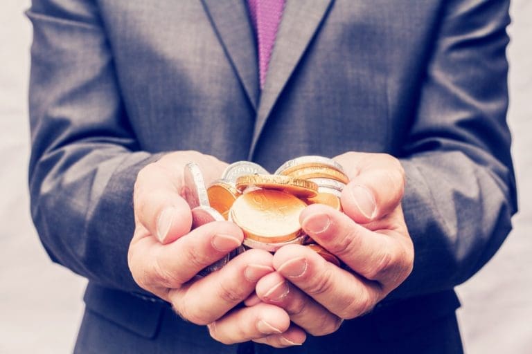 A businessman in a suit holding a handful of a gold and silver coins money or cash n hands