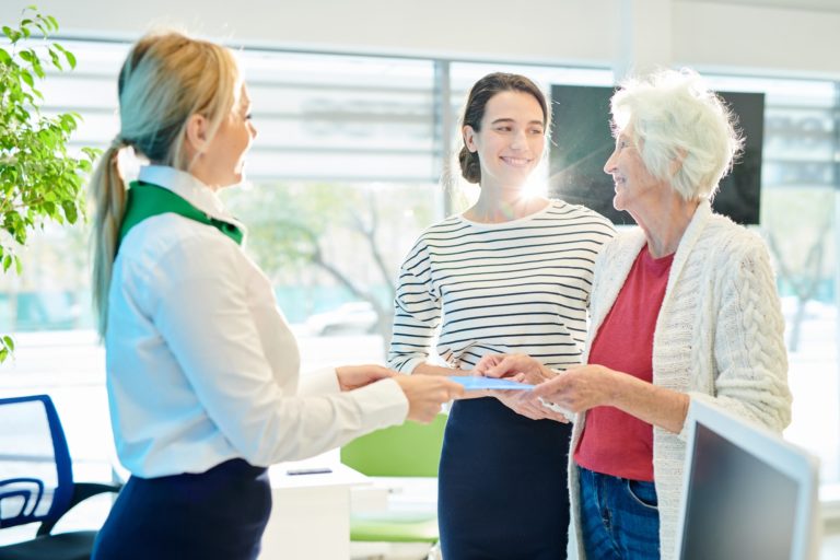 Bank manager giving folder with documents to old lady