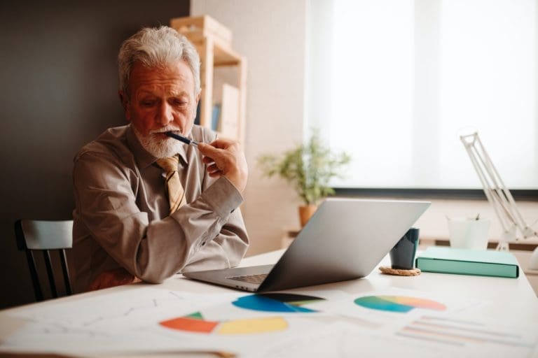 Mature businessman thinking about write news article while working an office.