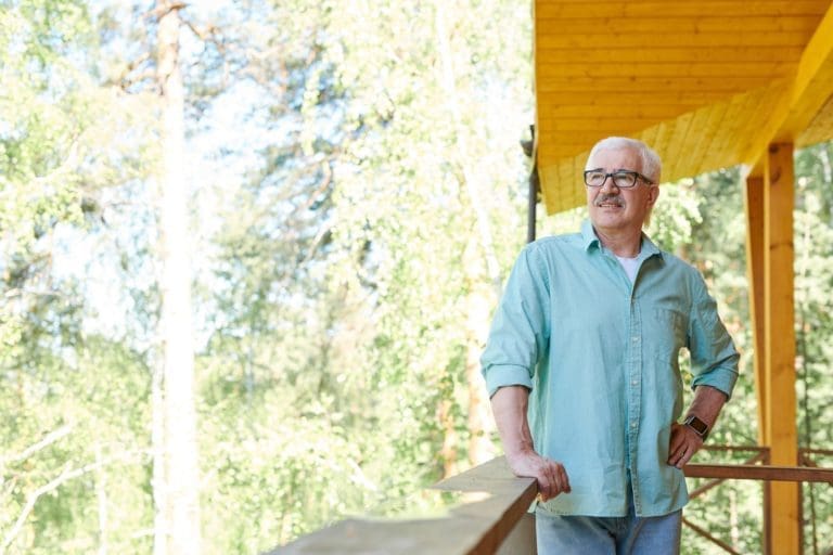 Happy mature retired man in casualwear relaxing in country house
