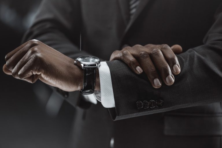 partial view of african american businessman checking time on watch